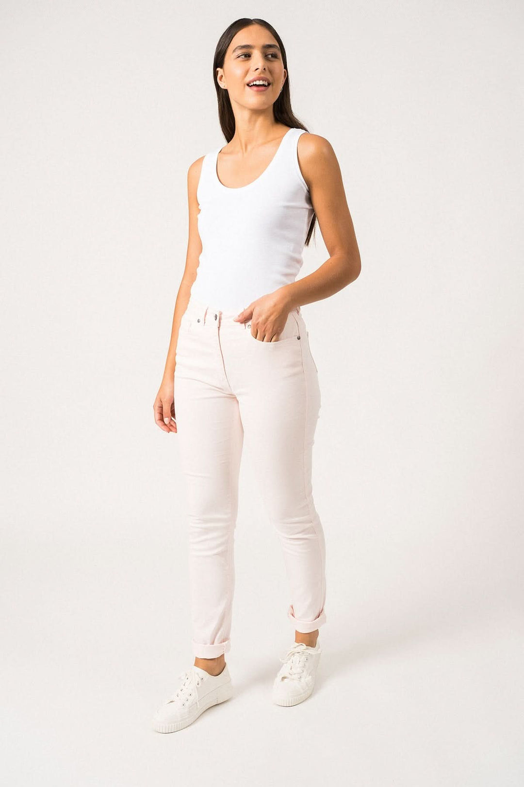 Femme portant un pantalon Mimosa couleur rose clair, avec un haut blanc, offrant confort et élégance.
