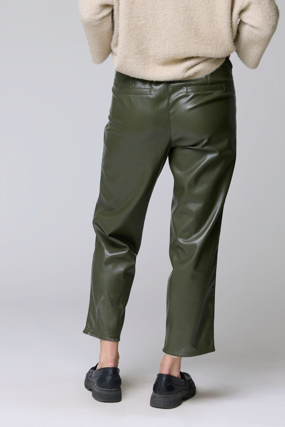 Pantalon Sabrna effet cuir en olive, coupe droite avec texture lustrée, porté avec un pull beige, vue de dos.