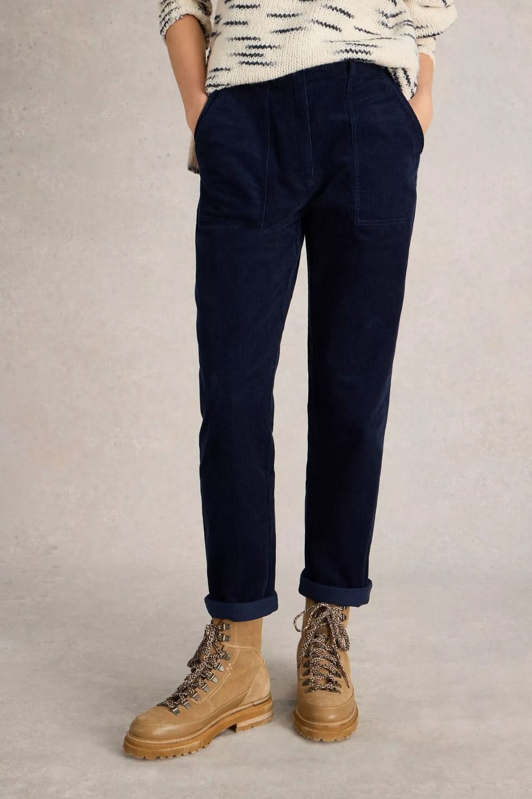 Pantalon Twister en velours côtelé bleu avec poches plaquées, coupe droite fuselée, porté avec chandail en maille et bottes.