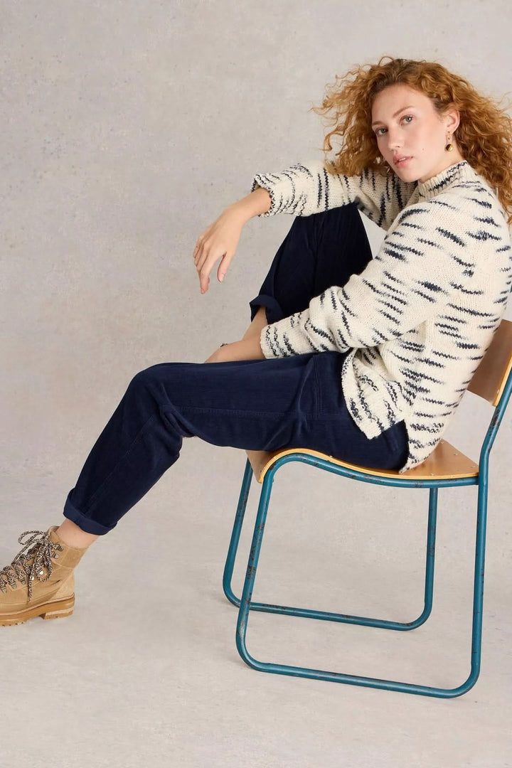 Alt Tag: Femme assise portant le Pantalon Twister en velours côtelé, coupe droite avec poches, look casual-chic avec chandail et bottes.