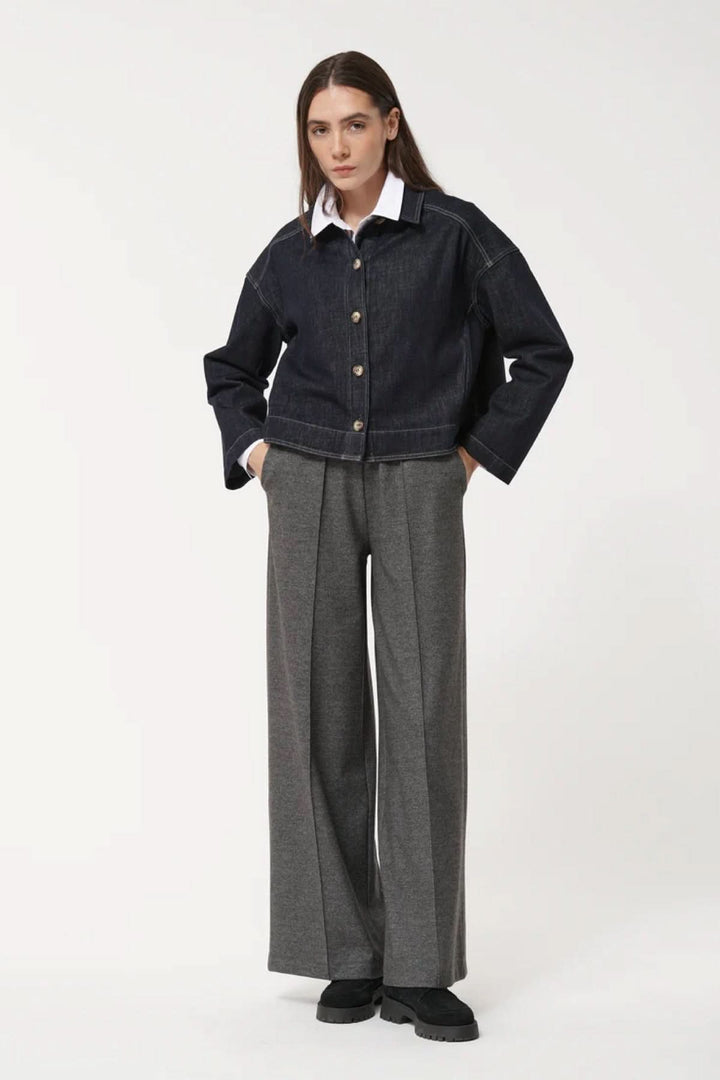 Femme portant un pantalon ample à la coupe fluide avec une veste en jean, alliant confort et modernité.