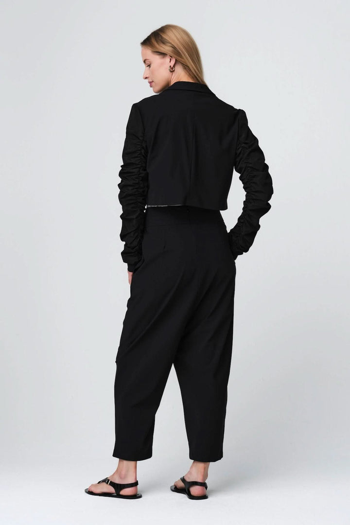 Woman wearing pantalon ample à taille structurée in black, showcasing fluid cut and contemporary style.