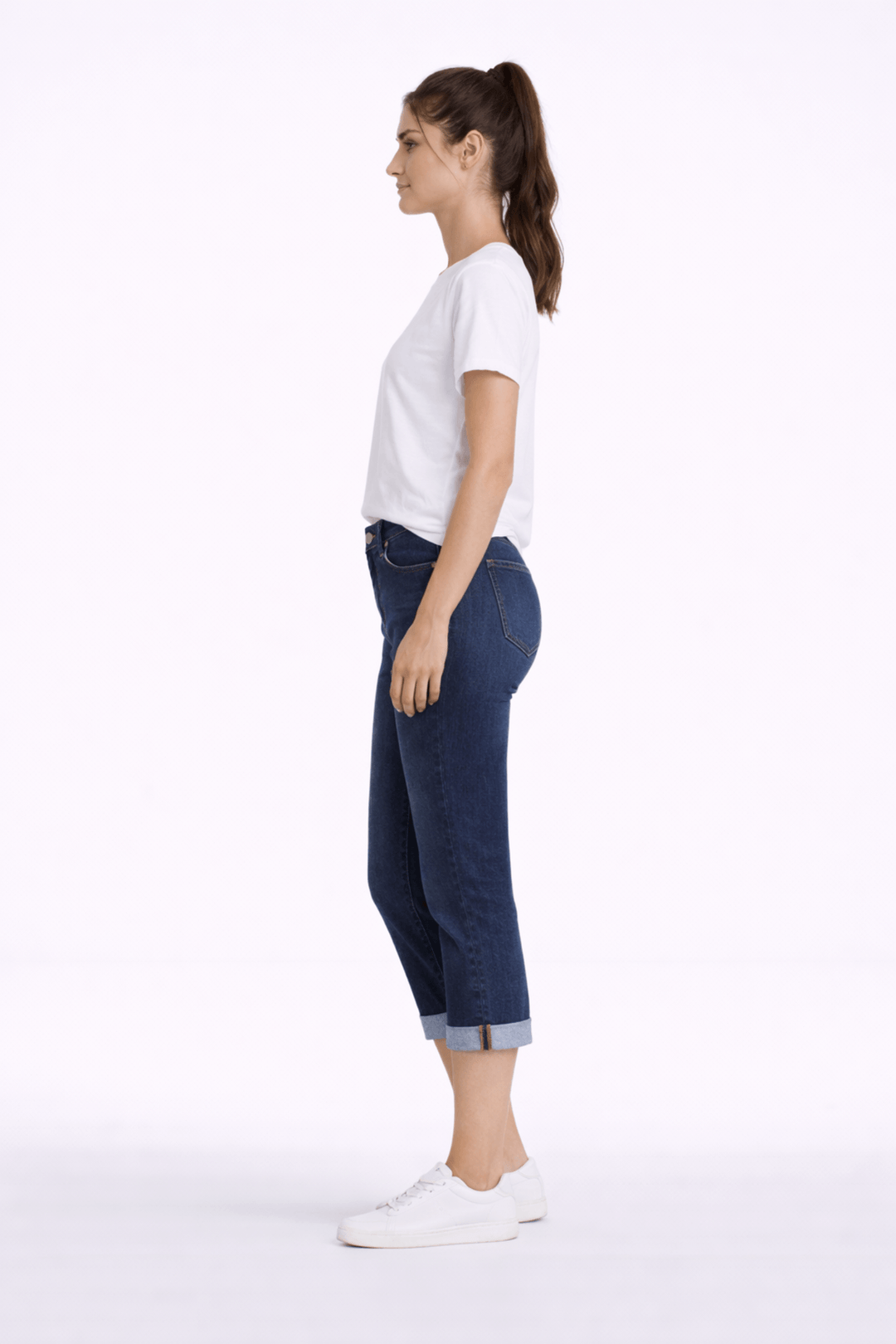 Jeune femme portant un pantalon capri ajusté bleu avec t-shirt blanc, coupe au mollet, idéale pour un look moderne et confortable.