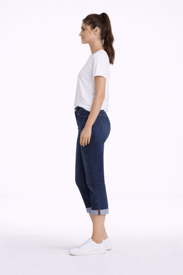 Jeune femme portant un pantalon capri ajusté bleu avec t-shirt blanc, coupe au mollet, idéale pour un look moderne et confortable.