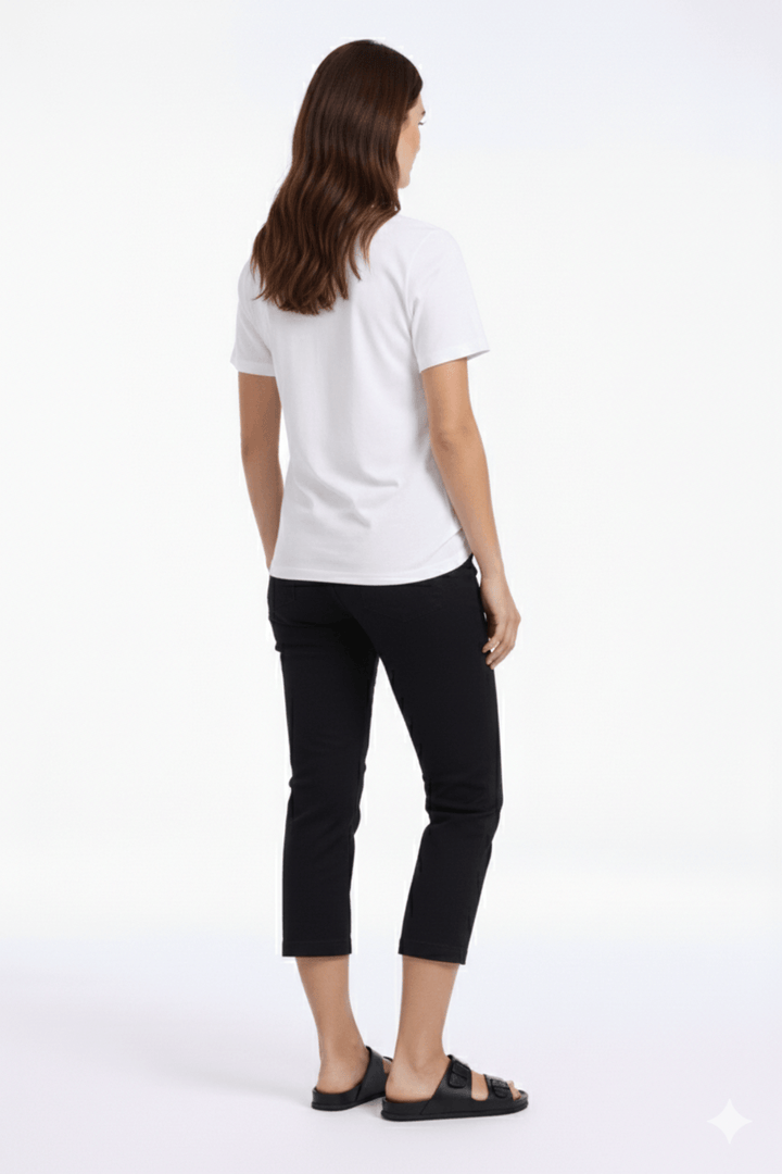 Femme portant un pantalon capri ajusté noir avec t-shirt blanc, montrant une silhouette moderne et épurée.