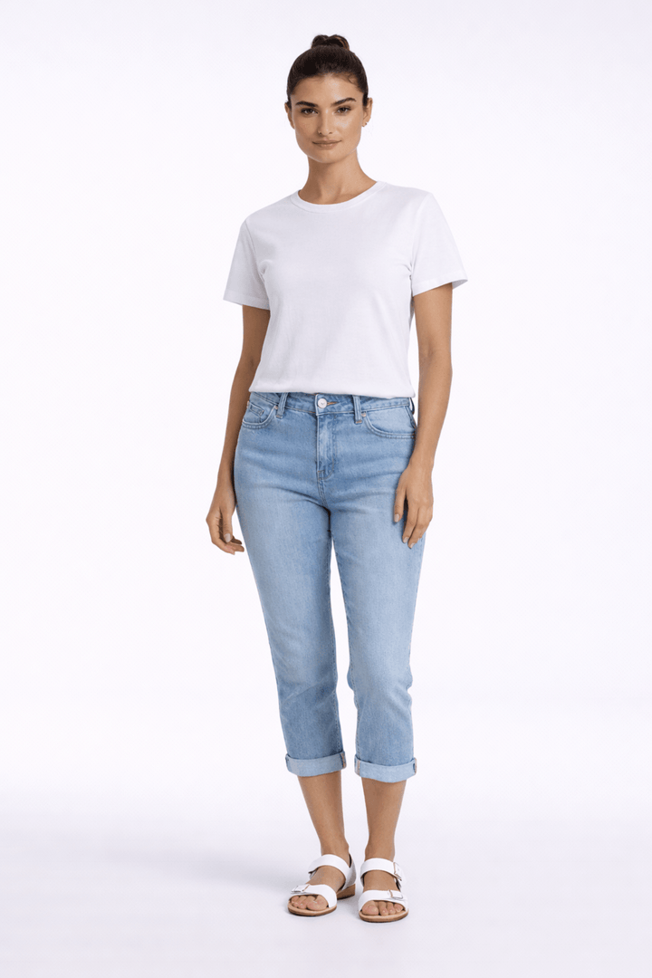 Pantalon capri ajusté en denim bleu, confort et style moderne pour une tenue quotidienne casual avec t-shirt blanc et sandales.
