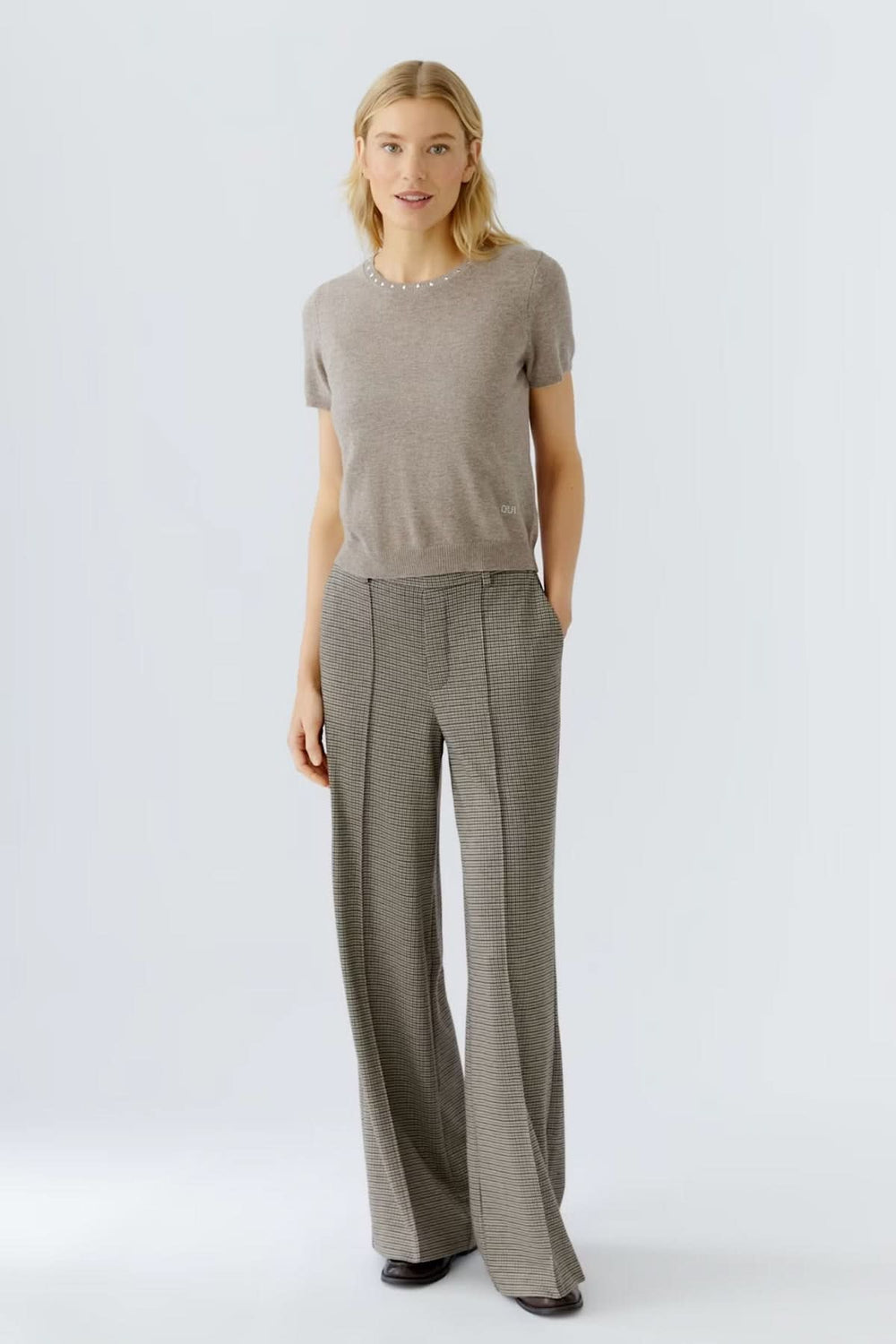 Femme portant un pantalon à carreaux large et fluide avec un chandail ajusté, style professionnel élégant.