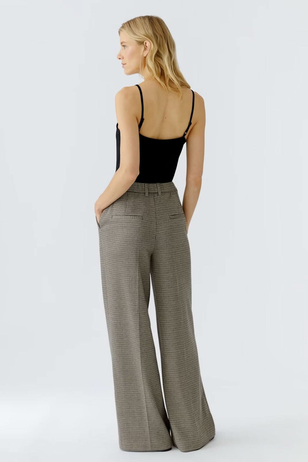 Pantalon à carreaux large et fluide avec taille régulière, porté par une femme de dos en tenue chic. Coupe élégante et professionnelle.
