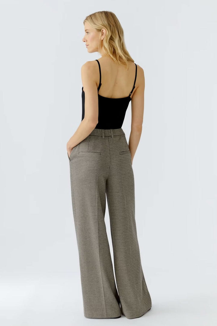 Pantalon à carreaux large et fluide avec taille régulière, porté par une femme de dos en tenue chic. Coupe élégante et professionnelle.
