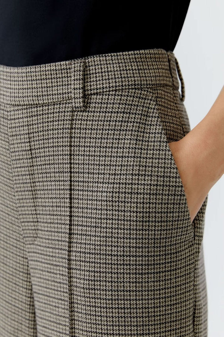 Pantalon à carreaux avec coupe large et plis marqués, porté avec élégance, idéal pour un look professionnel raffiné.