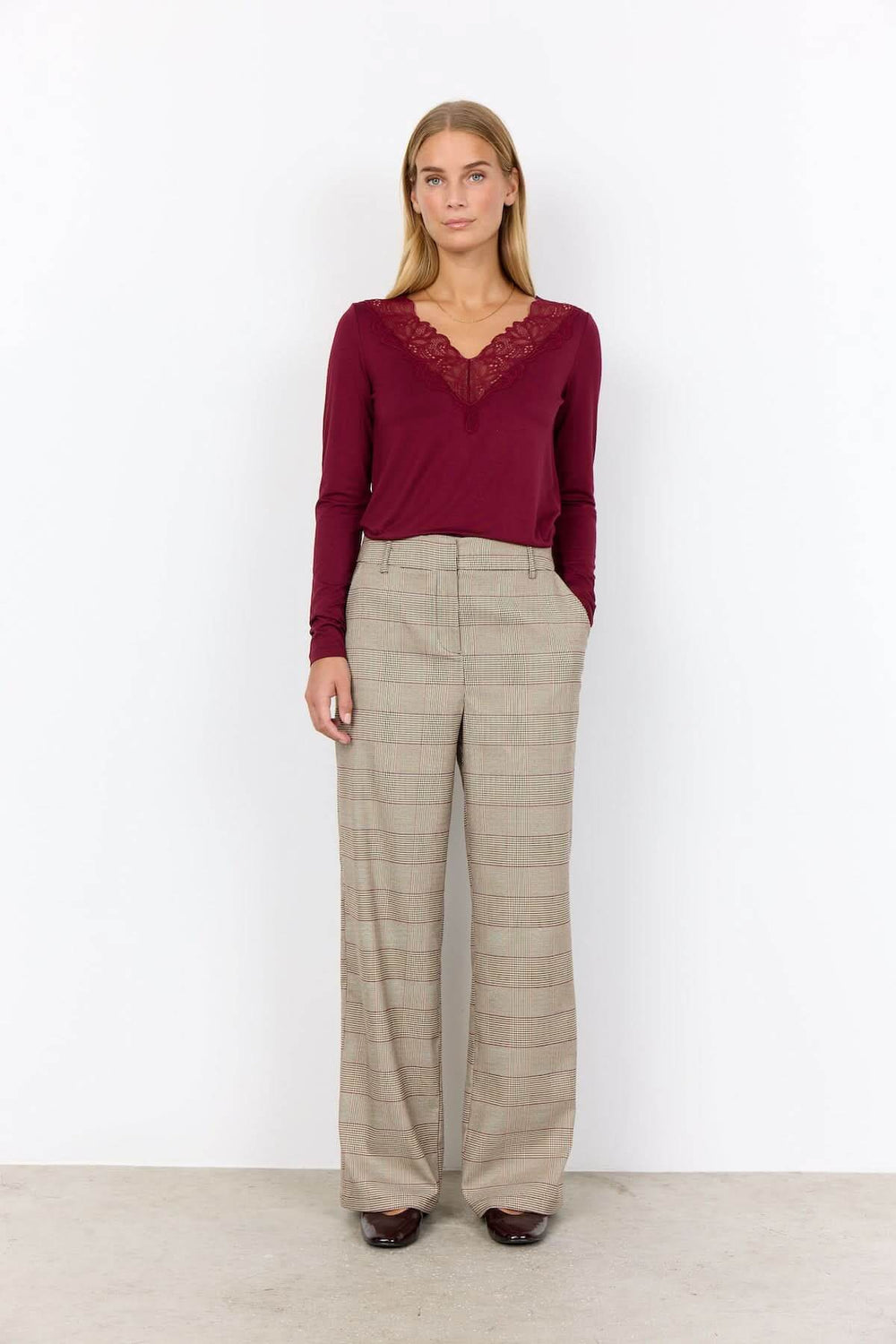 Pantalon à carreaux en coupe large avec motif prince-de-galles pour un look classique et moderne, porté avec un haut élégant.