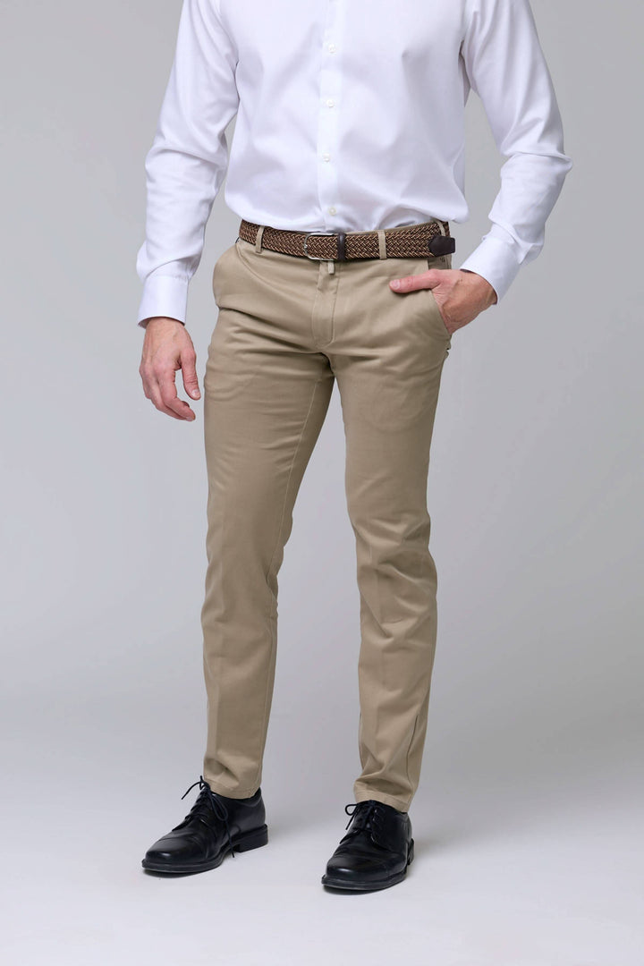 Homme portant un pantalon chino ajusté beige, coupe moderne, avec chemise blanche, parfait pour un look professionnel et décontracté.