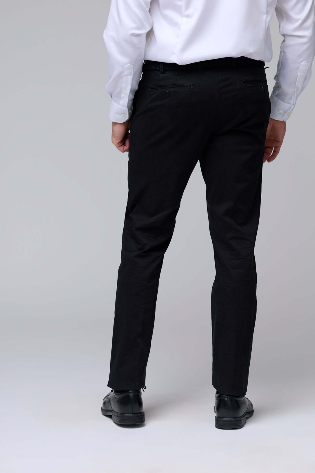 Homme portant un pantalon chino ajusté noir de dos, coupe moderne et confortable, idéal pour un look professionnel et décontracté.
