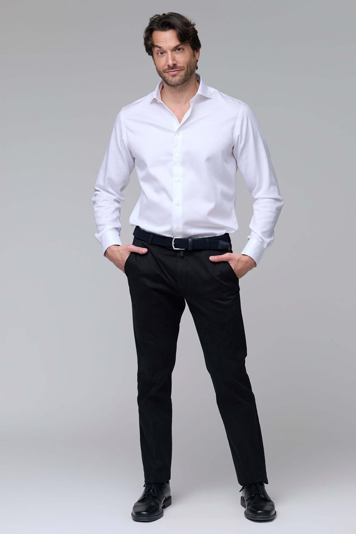 Homme portant un pantalon chino ajusté noir avec une chemise blanche, illustrant un look moderne et professionnel.