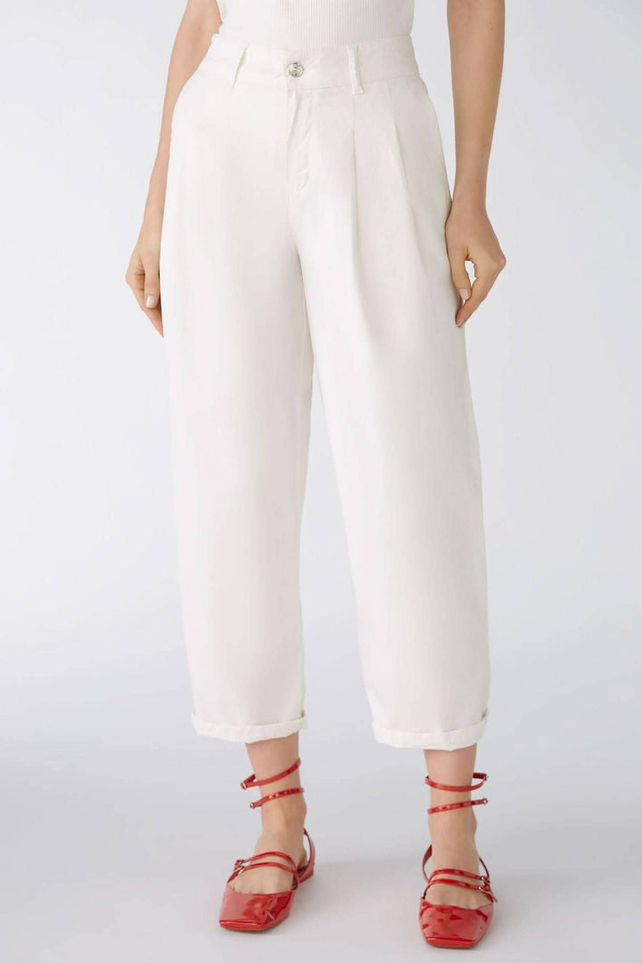 Pantalon blanc ample avec poches, longueur mollet, porté avec des chaussures rouges.