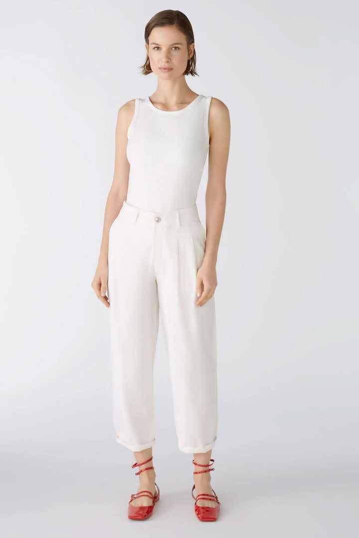 Femme portant un pantalon coupe ample blanc avec un haut sans manches, style décontracté et élégant.