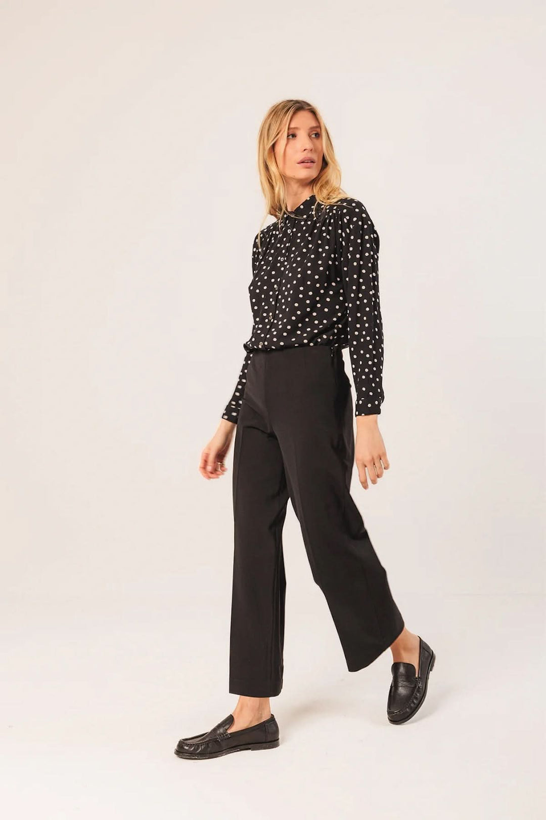 Femme portant un pantalon droit à coupe fluide noir avec une chemise à motifs, soulignant l'élégance et le confort.
