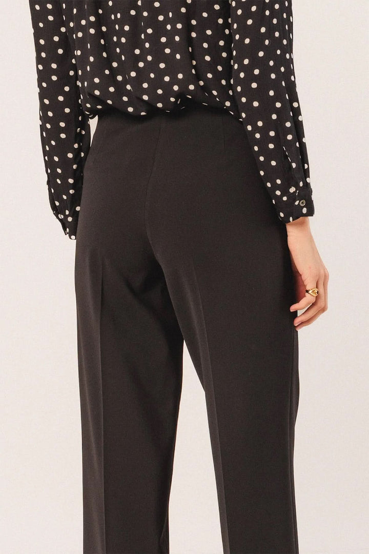 Vue arrière du pantalon droit à coupe fluide en noir, associé à une chemise à pois, taille mi-haute, élégant et confortable.