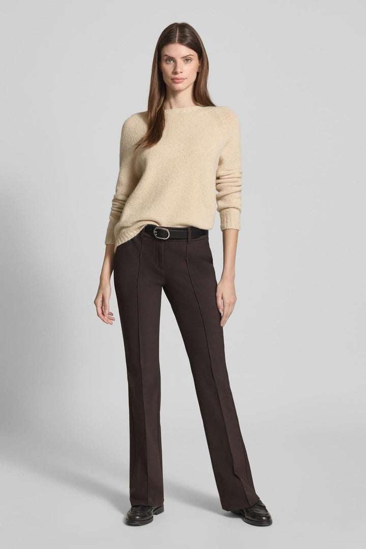 Femme portant un pantalon droit évasé à plis marqués, élégant et confortable, avec un chandail douillet beige.