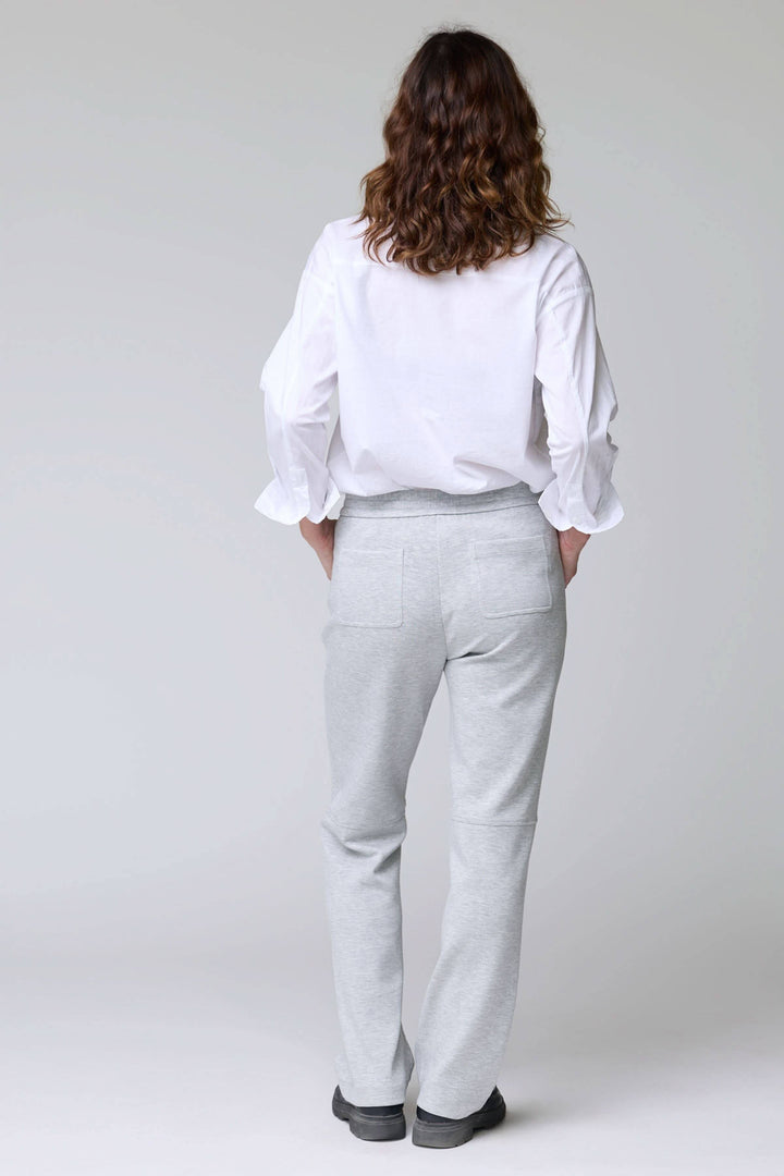 Pantalon en jersey ajustable gris avec taille élastique et poches, vue arrière sur mannequin portant une chemise blanche.