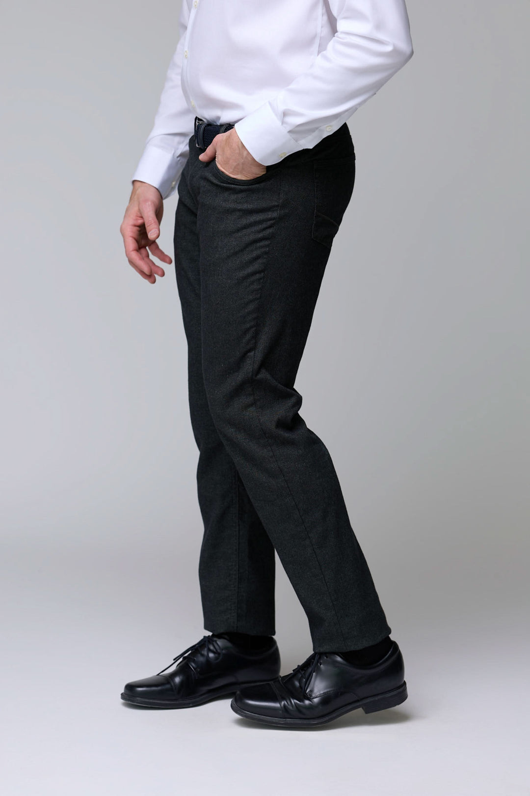 Pantalon en laine extensible noir porté par un homme avec chemise blanche et chaussures en cuir, coupe moderne et élégante.