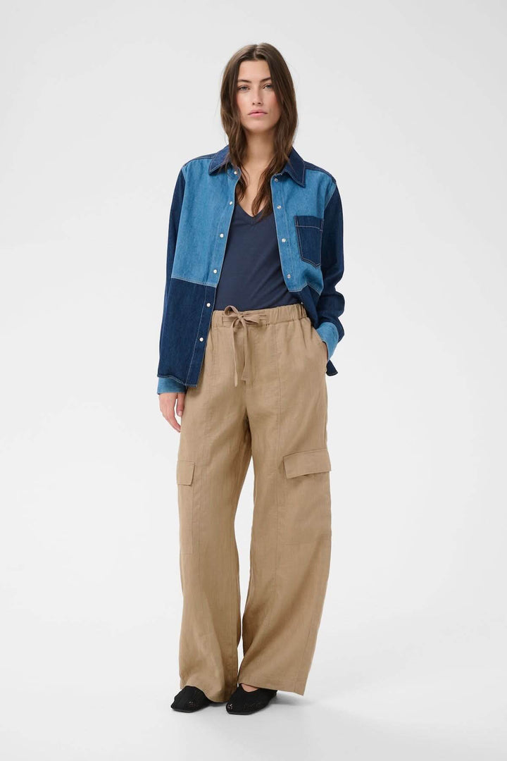 Femme portant un Pantalon en lin Atena, coupe droite et ample avec taille élastique ajustable et poches appliquées, esprit utilitaire et décontracté.
