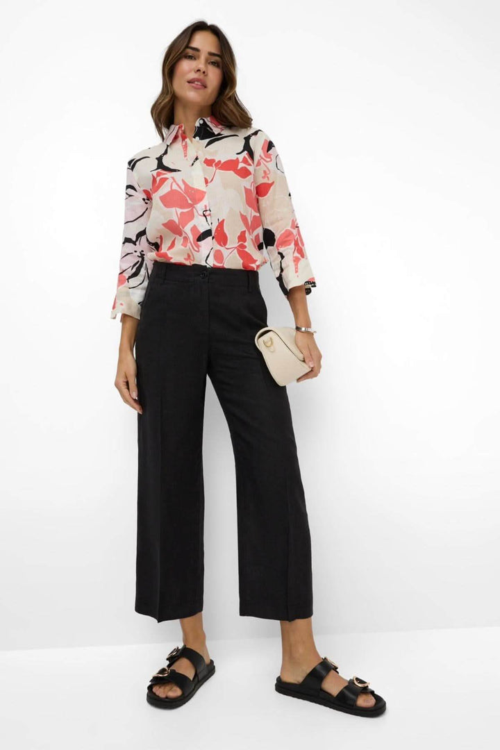 Femme portant pantalon en lin MAINE S, élégant et décontracté, avec chemisier à motifs floraux.