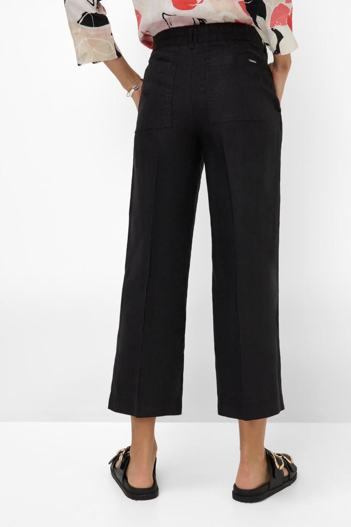 Femme portant un pantalon en lin MAINE S noir, montrant le dos avec poches arrière et jambes évasées.