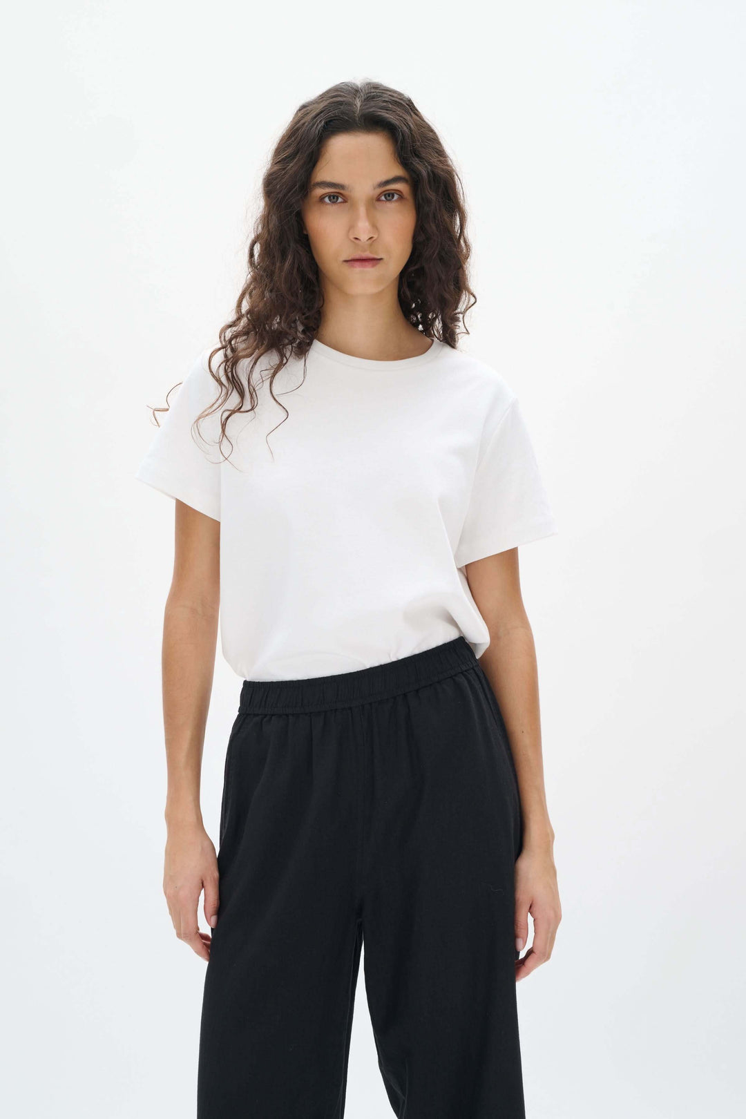 Femme portant un t-shirt blanc et un pantalon noir en lin, affichant élégance et confort.