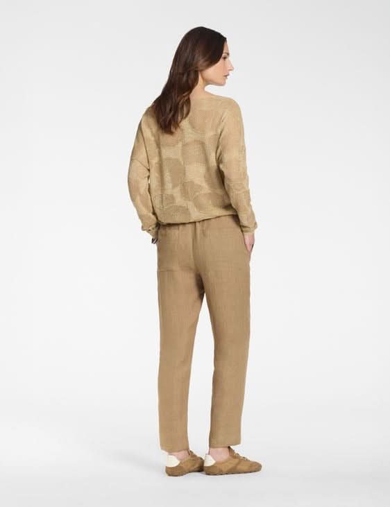 Femme portant un pantalon en lin à taille élastique, vue de dos, matière légère et respirante, tenue décontractée et moderne.