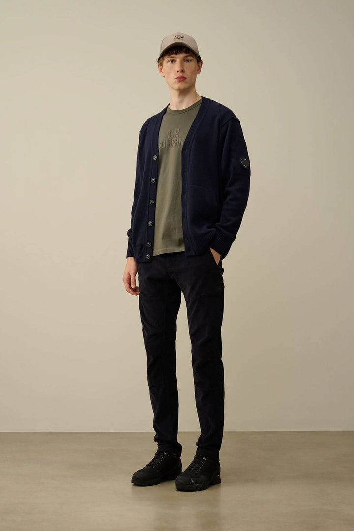Homme portant un cardigan navy, t-shirt olive et pantalon noir, affichant un style décontracté moderne.