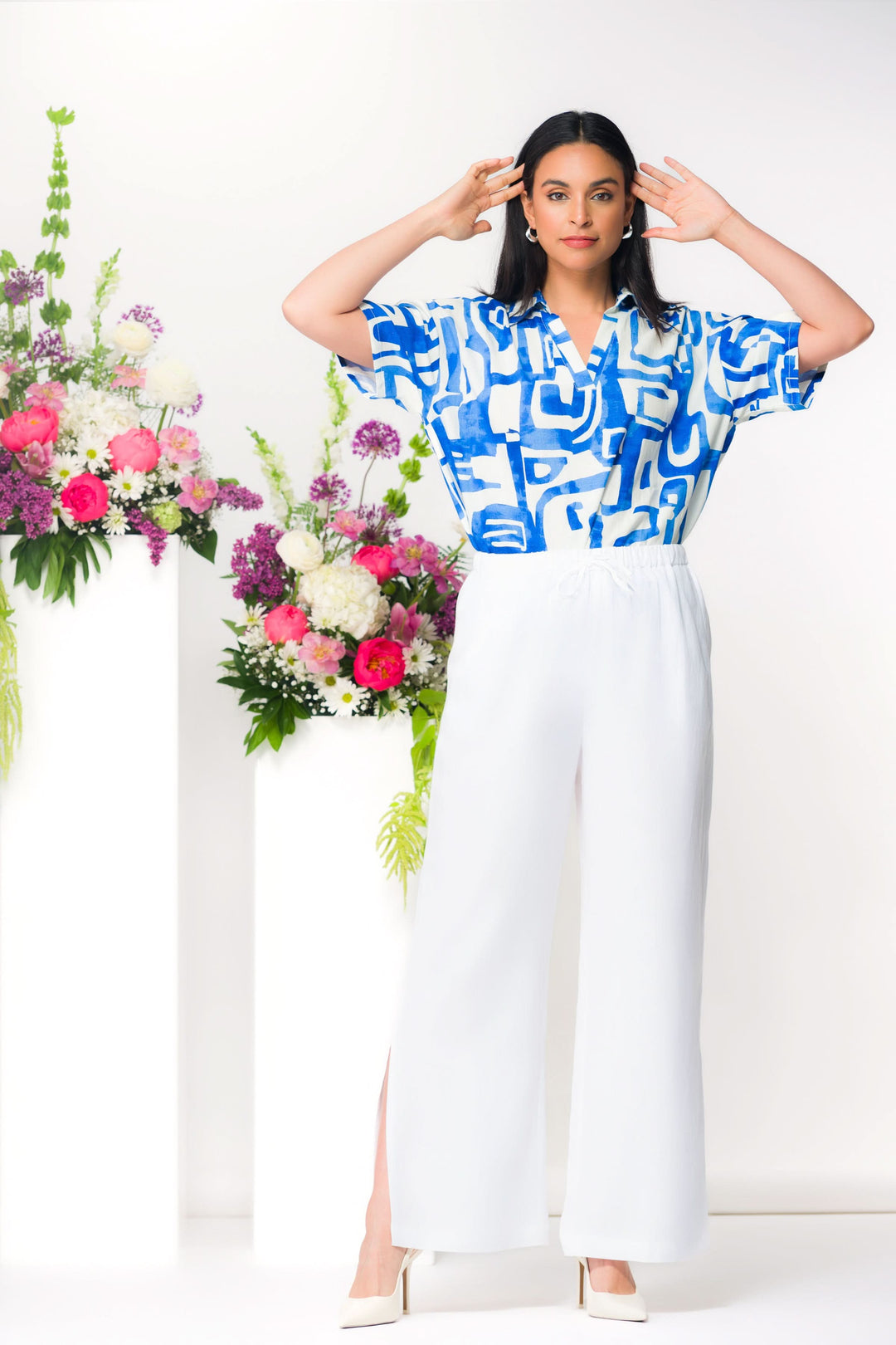 Pantalon fluide à fente latérale porté par modèle devant des fleurs colorées.