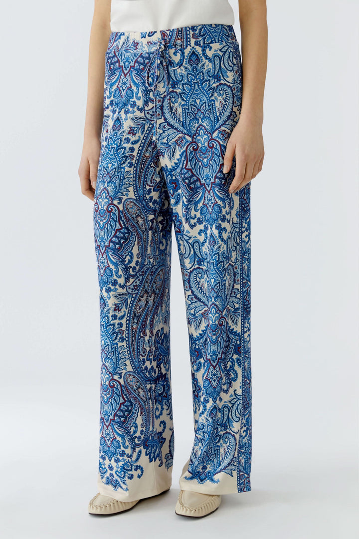Pantalon fluide à imprimé cachemire avec coupe droite légèrement évasée, porté par une personne pour un look bohème et raffiné.