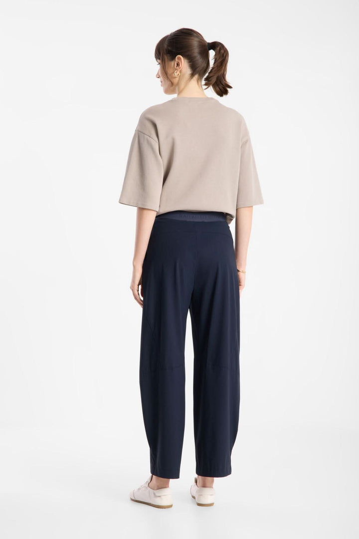 Femme portant un pantalon fluide à jambe large, vue de dos, montrant le tissu fluide et la silhouette moderne et épurée.