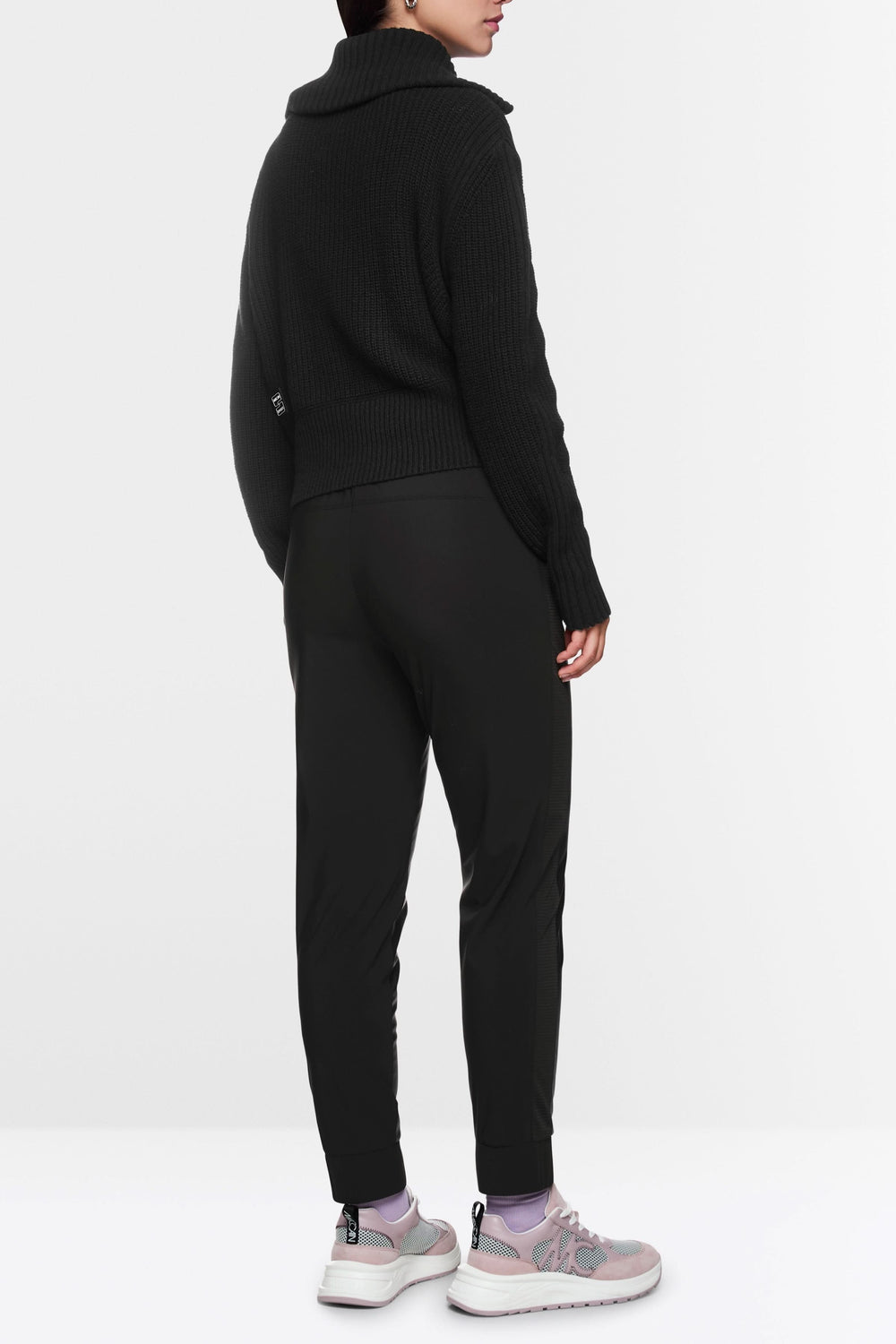 Vue arrière du Pantalon habillé Rhodos effet cuir, taille élastique, coupe fuselée, porté avec un pull noir et des baskets roses.
