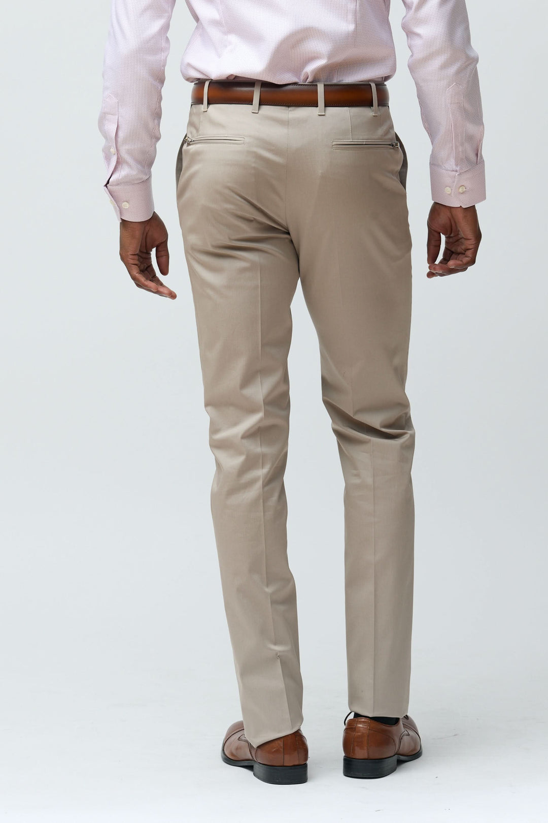 Homme portant un pantalon habillé coupe ajustée beige avec chemise rose, vue de dos, pour tenue professionnelle et élégante.