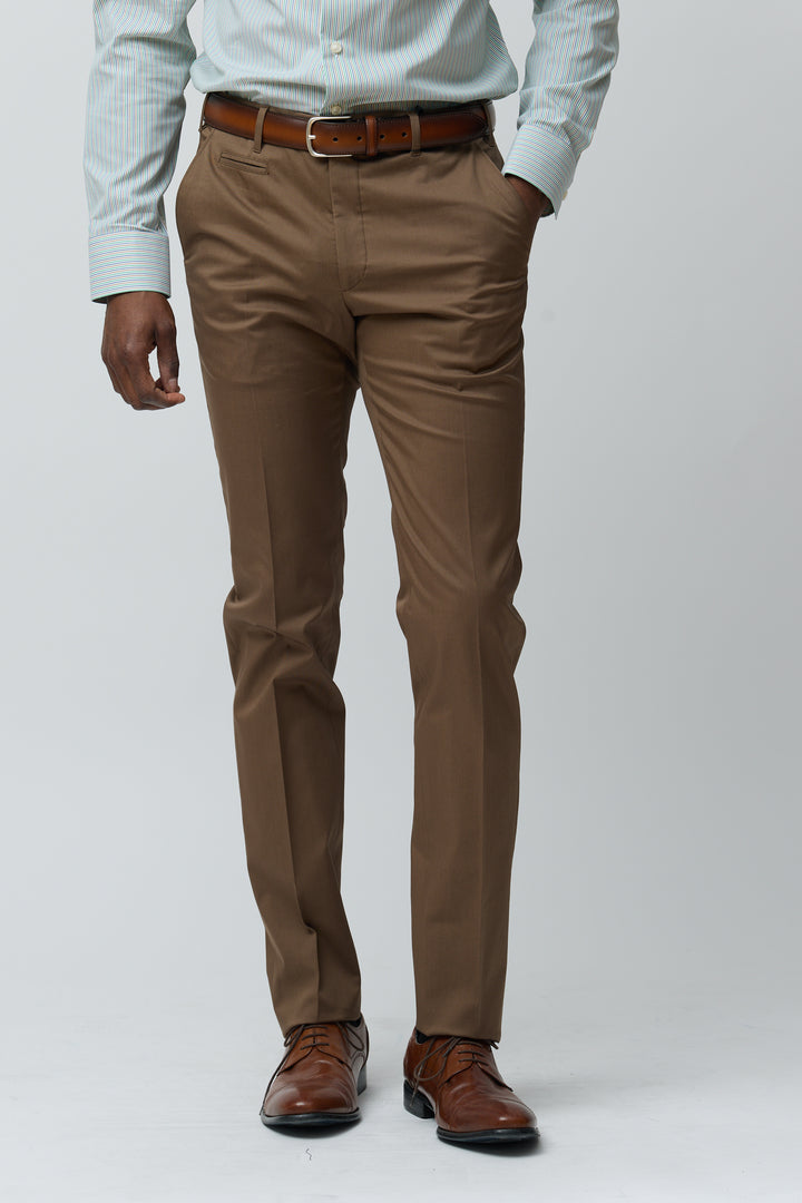 Homme portant un pantalon habillé coupe ajustée marron avec chemise bleue et ceinture marron, style élégant et décontracté.