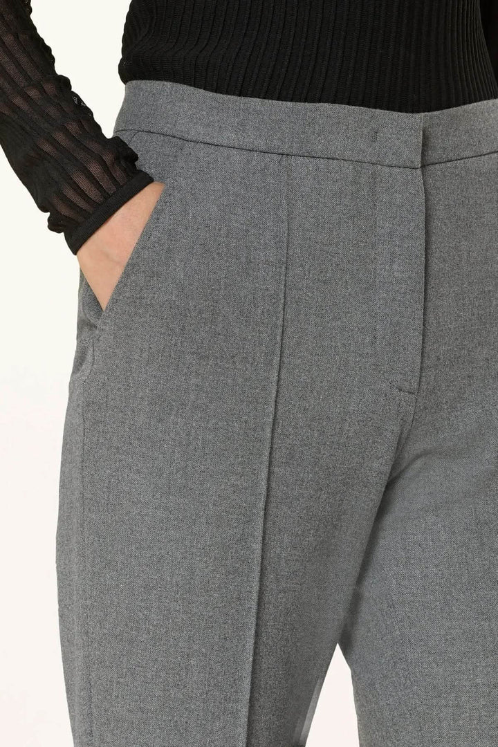 Pantalon habillé coupe évasée à plis marqués avec poches latérales, porté par une personne en haut noir.