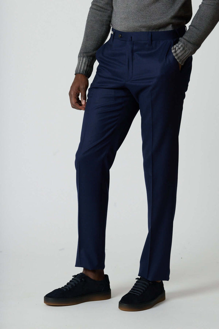 Homme portant un pantalon habillé en laine vierge avec poches zippées, coupe élégante et tombé impeccable, style professionnel moderne.