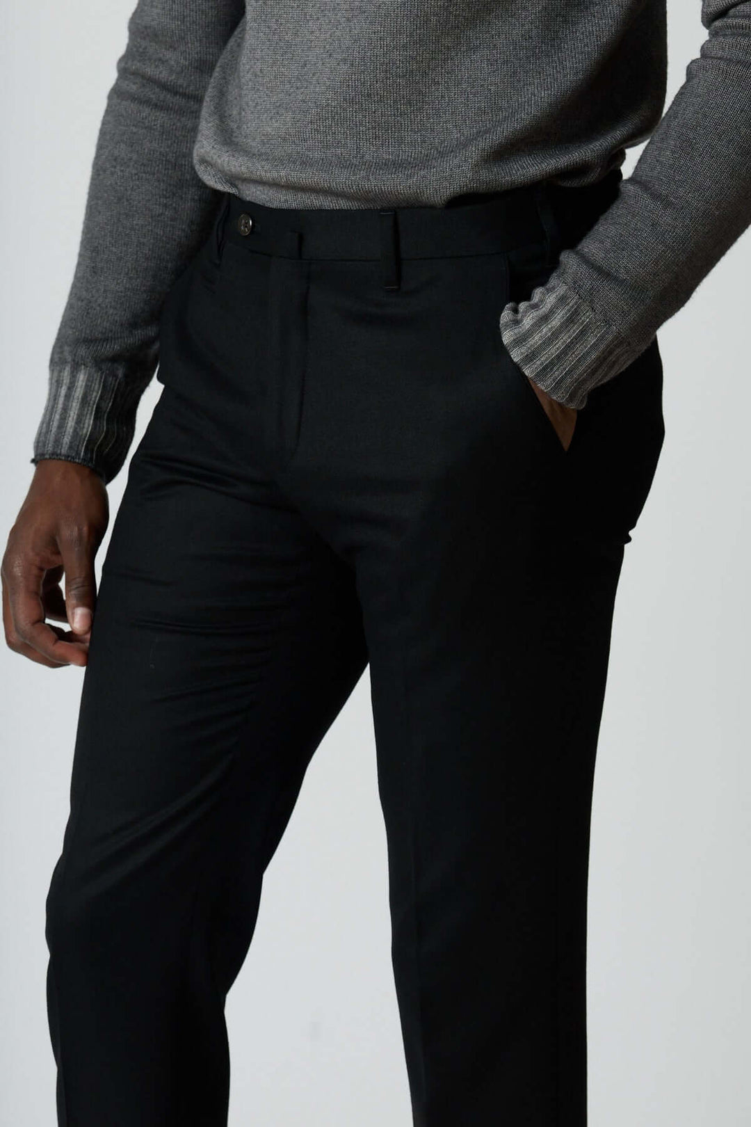 Homme portant un pantalon habillé en laine vierge avec poches arrière zippées pour un look élégant et moderne.