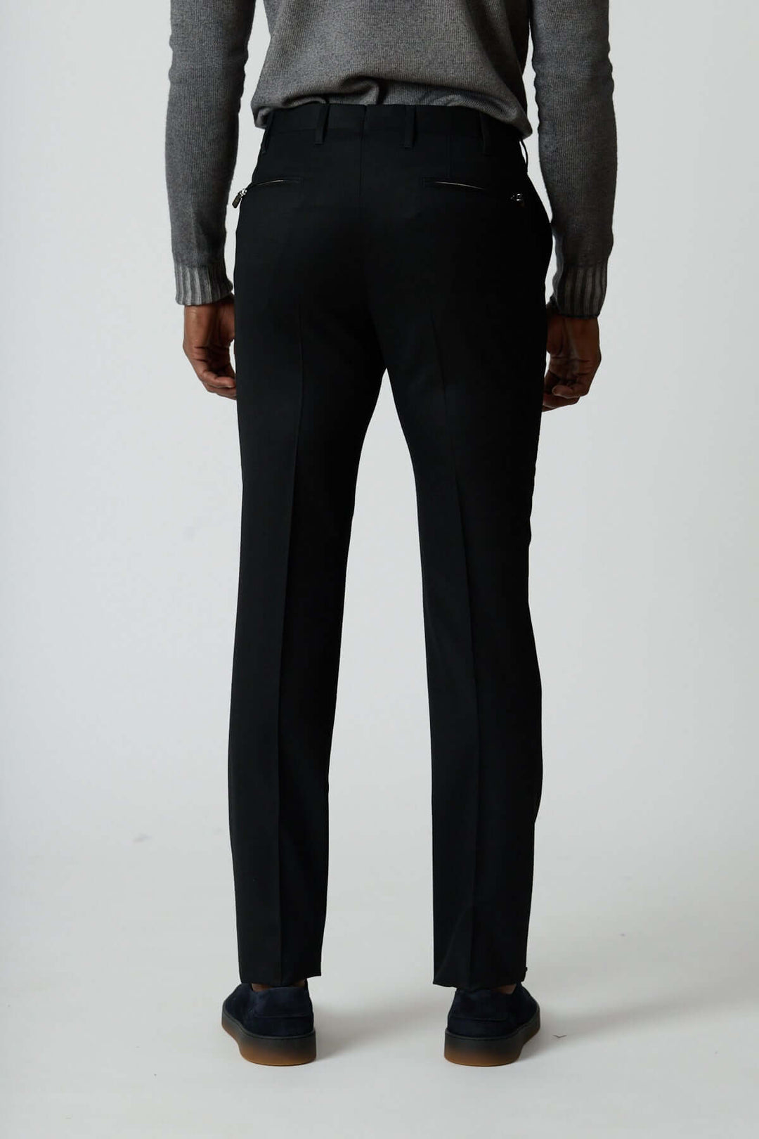 Pantalon habillé en laine vierge noir avec poches arrière zippées, montré de dos pour en souligner la coupe élégante et moderne.