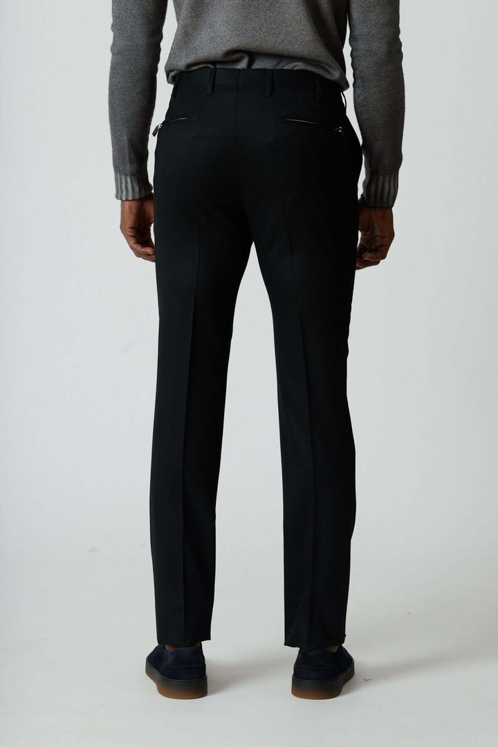 Pantalon habillé en laine vierge noir avec poches arrière zippées, montré de dos pour en souligner la coupe élégante et moderne.