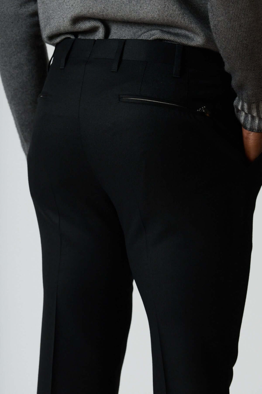Pantalon habillé en laine vierge noir avec poches arrière zippées et coupe élégante pour un style professionnel moderne.