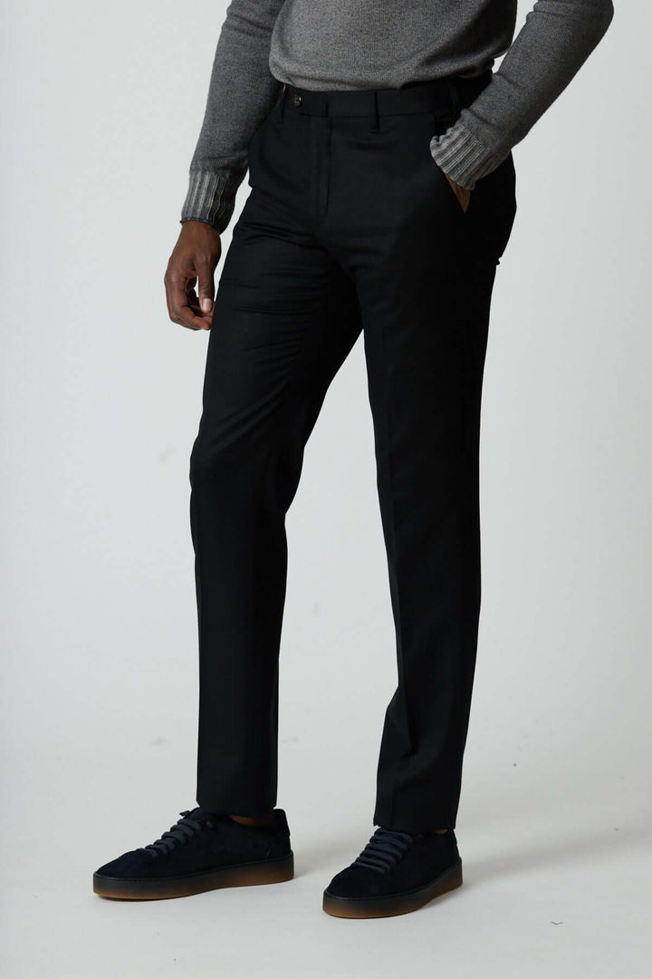 Homme portant un pantalon habillé en laine vierge noir avec poches zippées pour un style élégant et moderne.