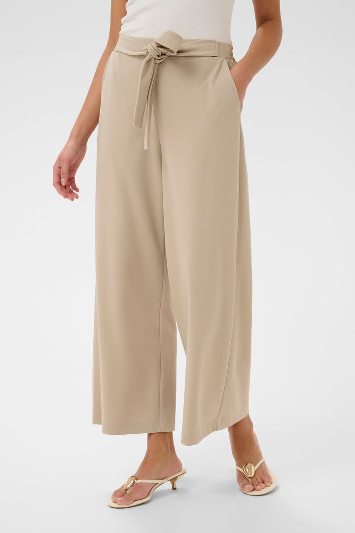Pantalon jambe large Phoebe beige avec ceinture intégrée, offrant élasticité et style pour un look élégant et polyvalent.