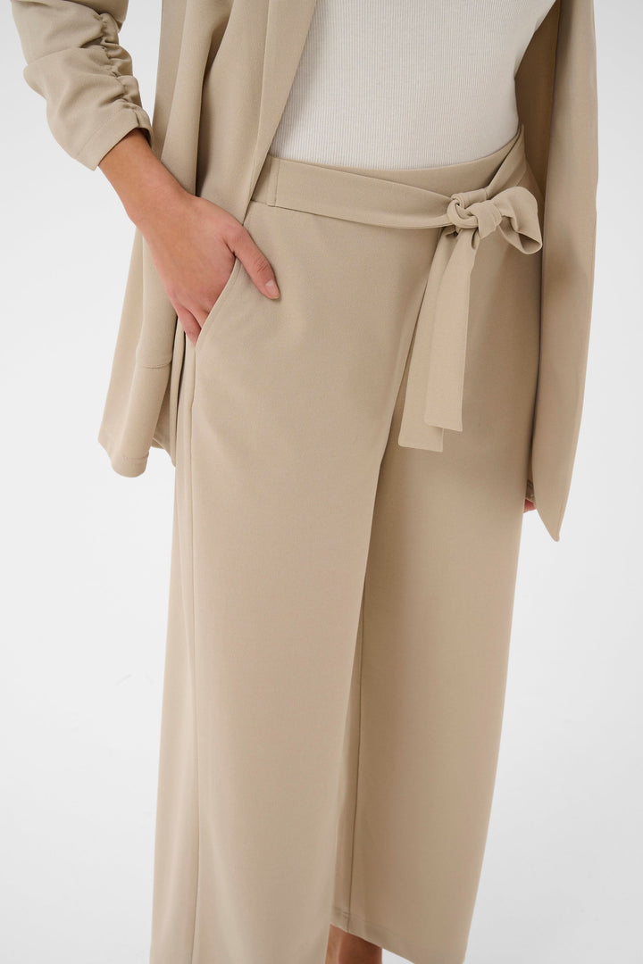 Pantalon jambe large Phoebe en tissu beige avec ceinture intégrée, coupe élégante et confortable pour un style polyvalent.