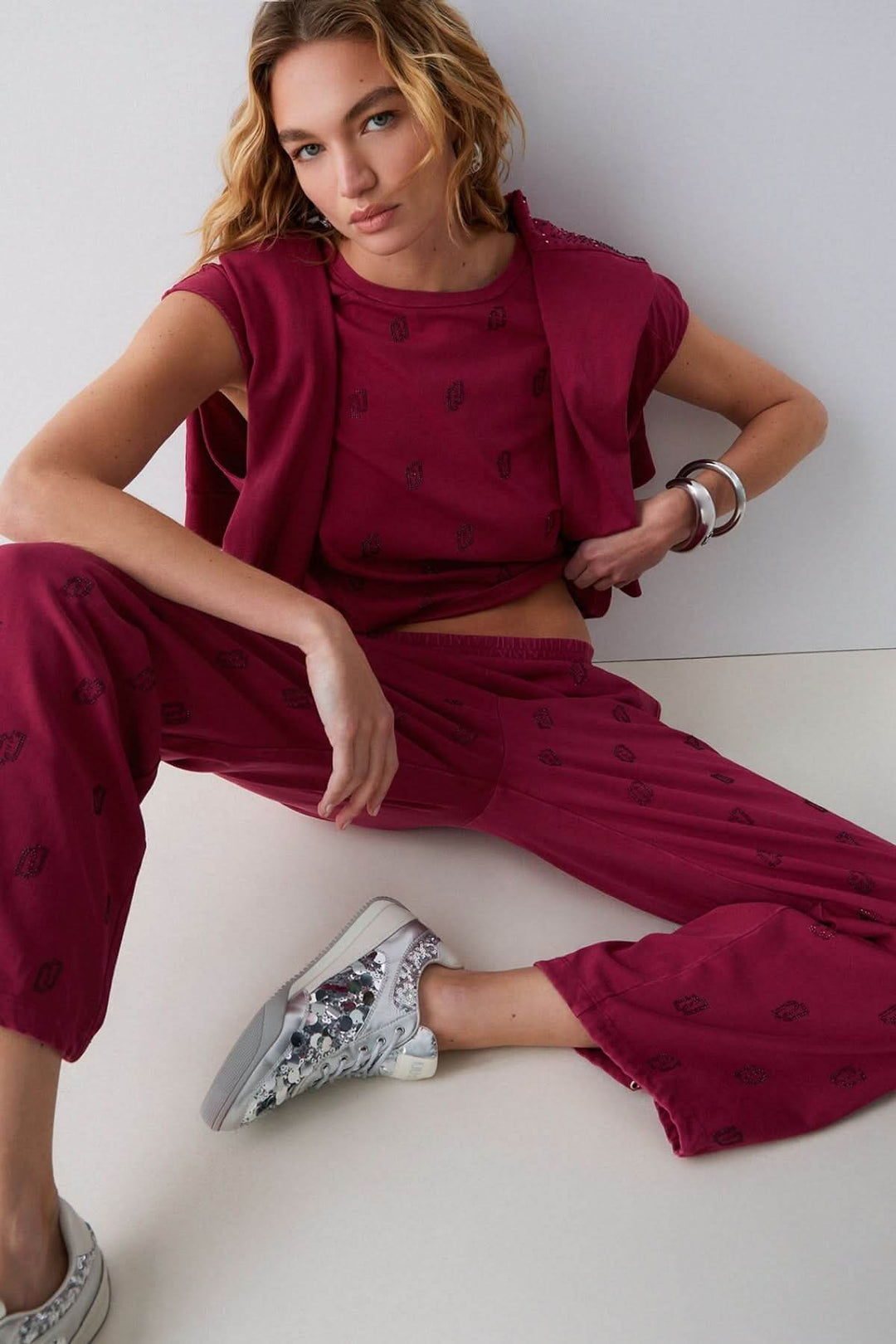 Femme portant un pantalon jogging imprimé à jambe large, silhouette décontractée, motif distinctif, couleur bordeaux et tissu confortable.
