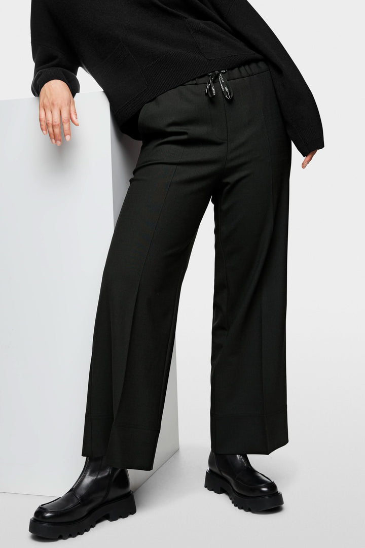 Femme portant un pantalon large noir avec taille élastique, style urbain contemporain, confort et élégance décontractée.