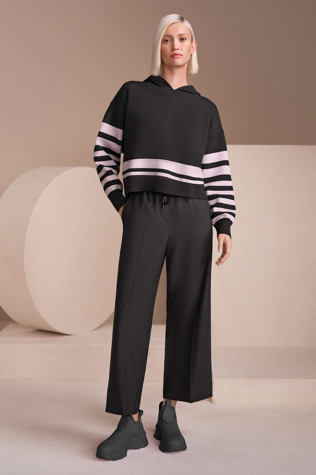 Femme portant un pantalon large élégant avec taille élastique et cordon de serrage, associé à un chandail et des chaussures tendance.