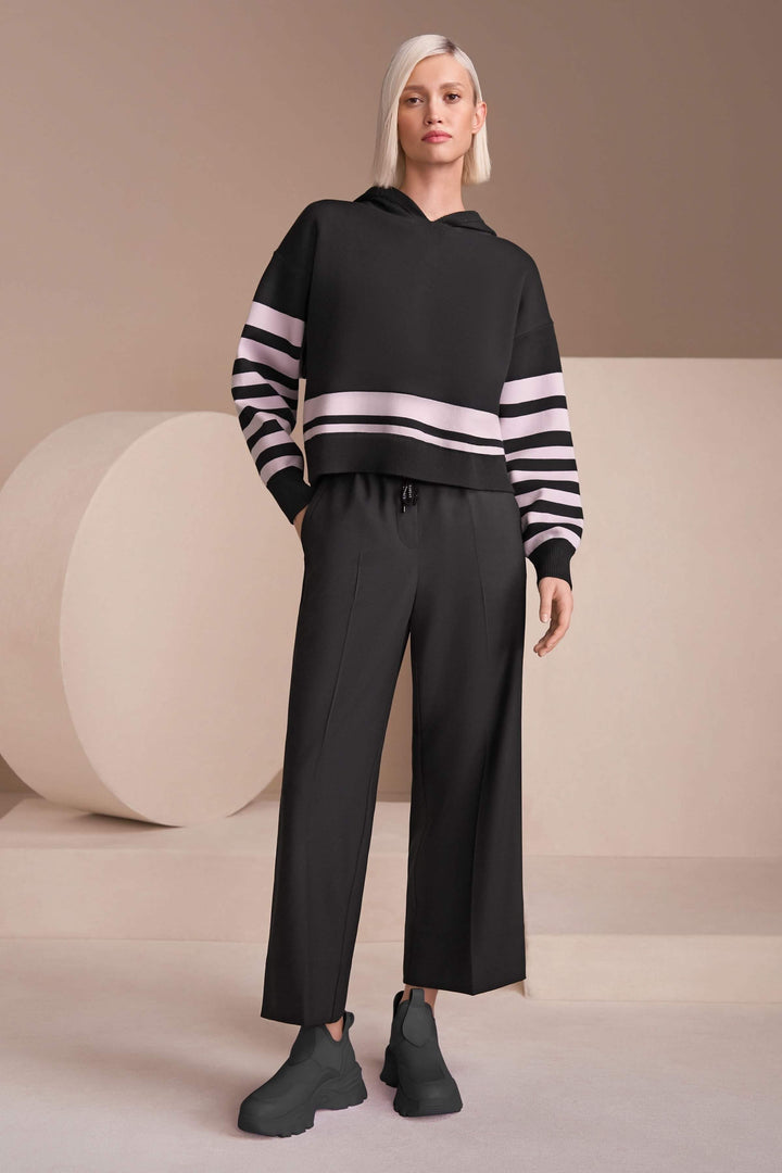 Femme portant un pantalon large élégant avec taille élastique et cordon de serrage, associé à un chandail et des chaussures tendance.